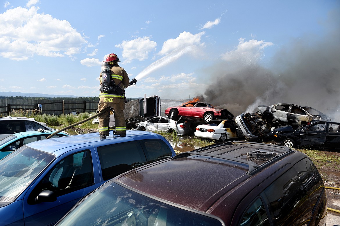 Evergreen Fire Rescue Captain James Boyce hoses down a fire in several vehicles in the junkyard at Tri City Auto & Wrecking along U.S. Highway 2 East near Glacier Park International Airport on Wednesday. Evergreen, Columbia Falls and West Valley fire departments responded to the fire, as well as GPIA’s Aircraft Rescue and Firefighting vehicle. (Casey Kreider/Daily Inter Lake)