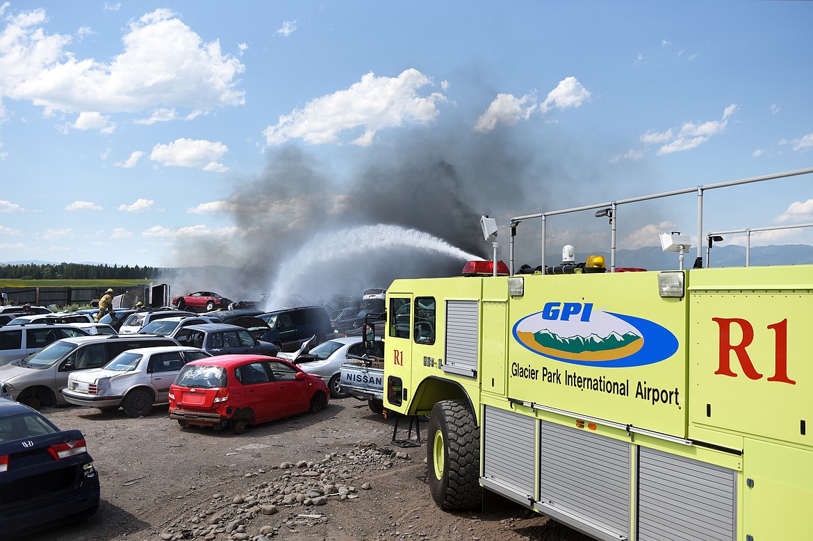 Glacier Park International Airport’s Aircraft Rescue and Firefighting vehicle hoses down a fire in several vehicles in the junkyard at Tri City Auto & Wrecking along U.S. Highway 2 East on Wednesday. Evergreen, Columbia Falls and West Valley fire departments also responded to the fire. (Casey Kreider/Daily Inter Lake)