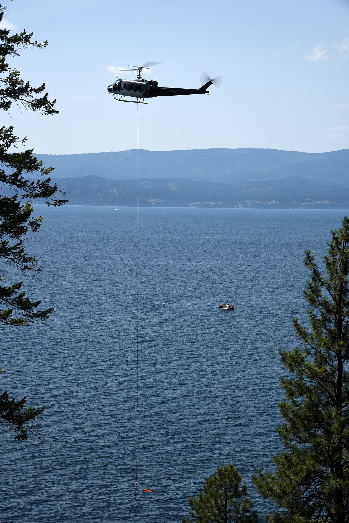 A helicopter dips a bucket into Flathead Lake Tuesday afternoon during efforts to douse a small wildfire on Crane Mountain near Woods Bay. The fire was estimated at less than an acre. (Butch Larcombe photo)