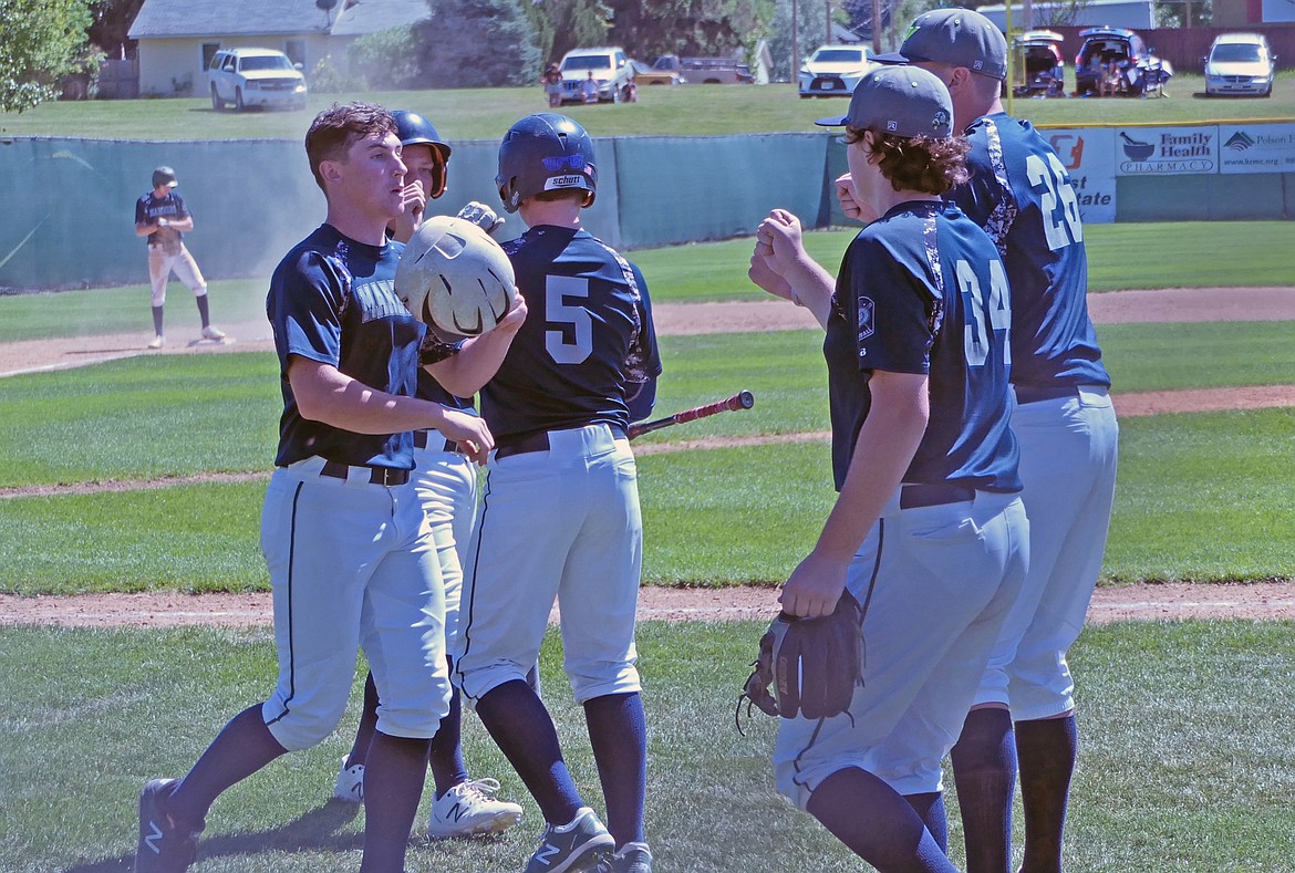 Mariners players celebrate as Eric Dolence and Xavier Fisher score a run each on a Keyan Dalby triple in the bottom of the sixth inning against the Glacier Twins on Saturday, July 25. (Whitney England/Lake County Leader)