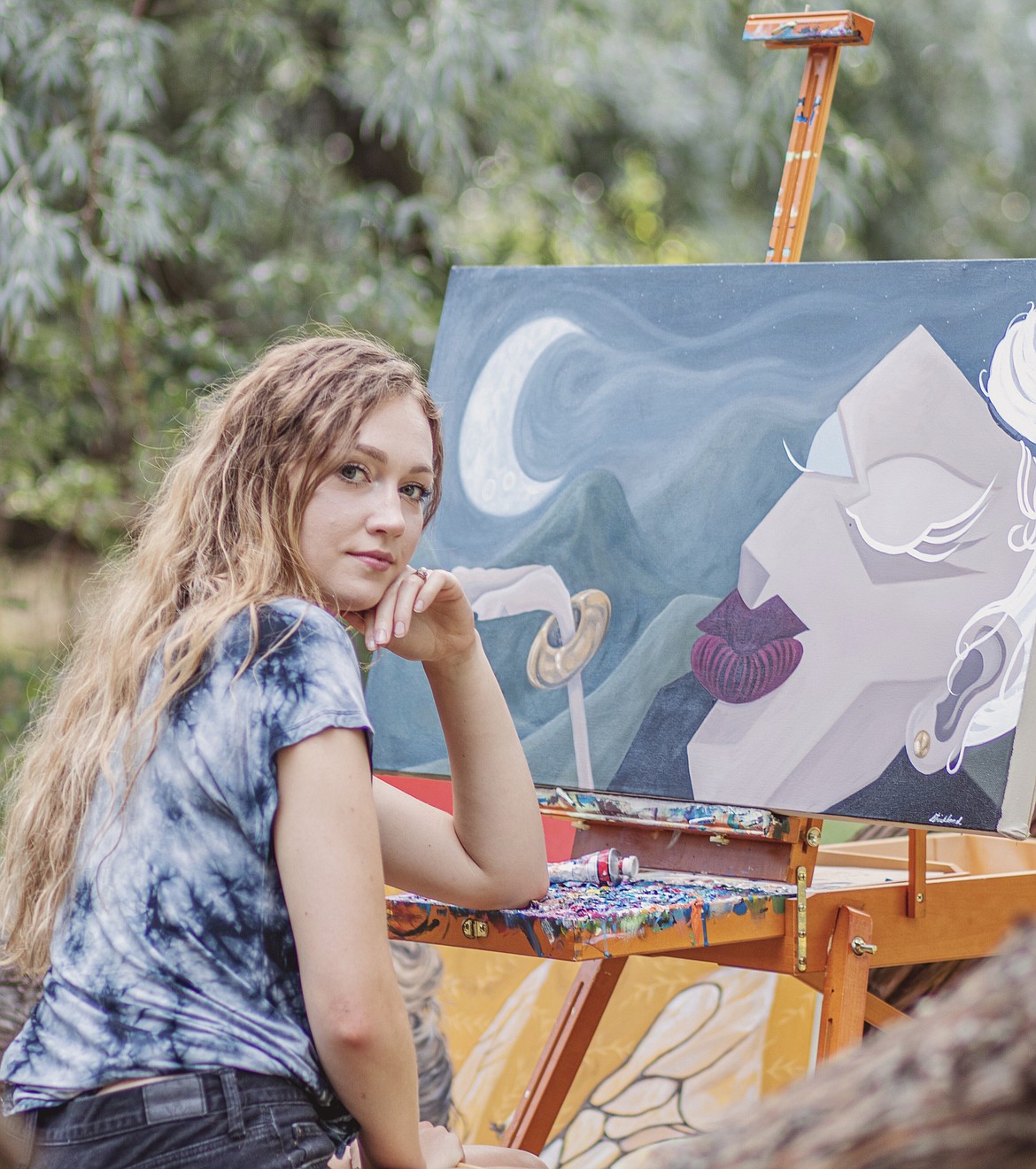 Moses Lake High School graduate Marissa Strickland poses with one of her paintings. Strickland recently earned a Bachelor of Fine Arts degree in studio art from Central Washington University.
