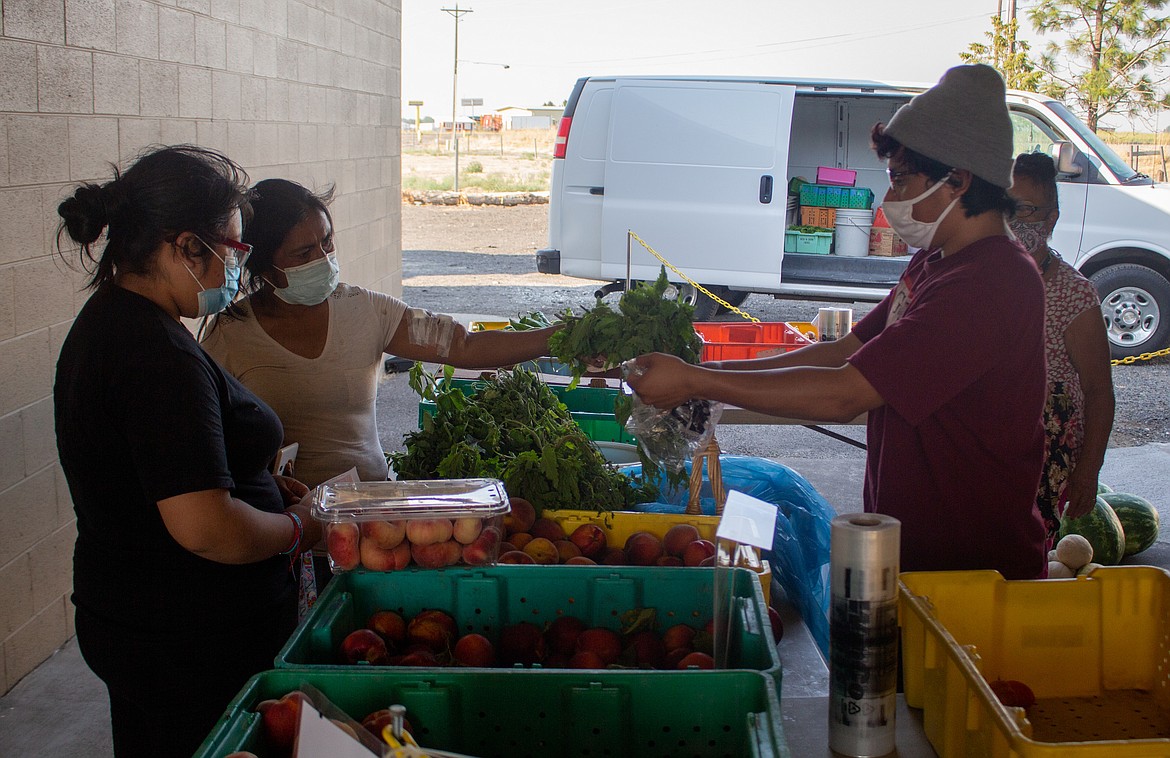 Isaac Hernandez helps out customers at the Othello Farmers Market on Thursday afternoon as the market comes to a close.