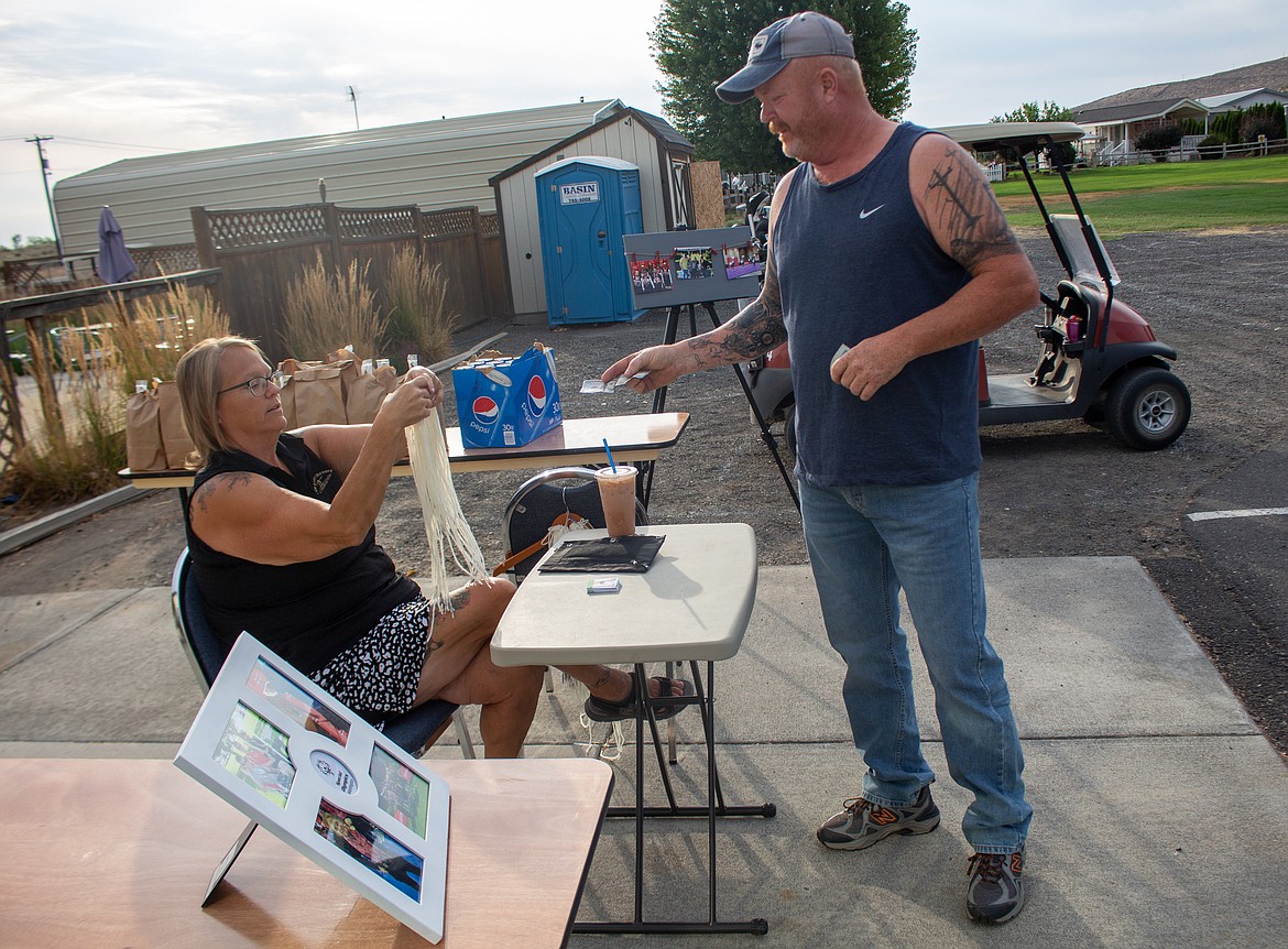 Casey McCarthy/The Sun Tribune
LegacY Golf Course Pro Shop Manager Noelle Beaushaw unwinds string for Travis Jenkins as part of one of the course’s tournament sidegames to help raise money for the Special Olympics organization.