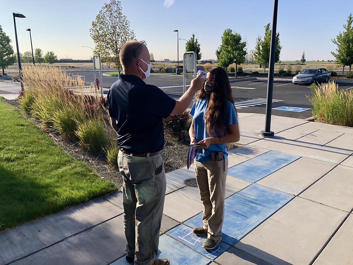 Dean of Students Chad Utter takes junior Maya Armacost-Felton’s temperature on Tuesday morning prior to the start of classes at the Columbia Basin Technical Skills Center. Armacost-Felton is one of 42 students attending two weeks of summer school classes at CBTech this August.