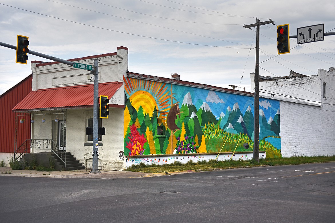 A mural created by artist Thomas Valencia along West Center Street at Fifth Avenue West in Kalispell on Thursday, Aug. 6. Valencia began working on the project about 10 days ago and used GoFundMe to crowdsource money for primer paint, low-pressure spray paint cans for the detail work and additional supplies. Valencia also seeks the community's help with filling the lower white panel of the mural with painted hand prints, as long as you don't mind getting a little spray paint on your hands. He primarily works on the project during the evening hours, which he received permission to complete from the building owner, Valley Linen, and the city of Kalispell. The mural features snowcapped mountains, rushing rivers and streams, wildlife, forests and flowers and will transition from a daylight to a nighttime scene from left to right. The mural will span an entire block when complete. (Casey Kreider/Daily Inter Lake)