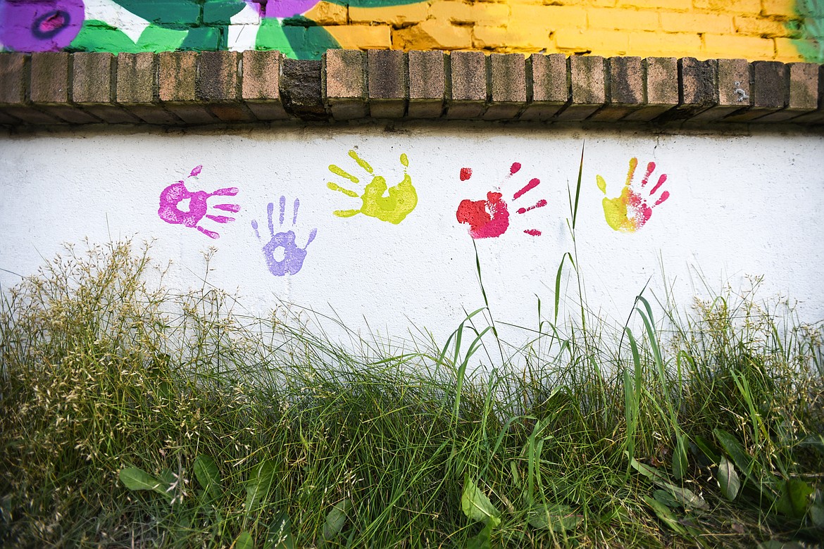 Painted hand prints decorate a wall below a mural created by Thomas Valencia along West Center Street and Fifth Avenue West in Kalispell on Tuesday, Aug. 4. Valencia is asking for the community's help in filling the horizontal panel with hand prints, as long as you don't mind getting spray paint on your hand. (Casey Kreider/Daily Inter Lake)