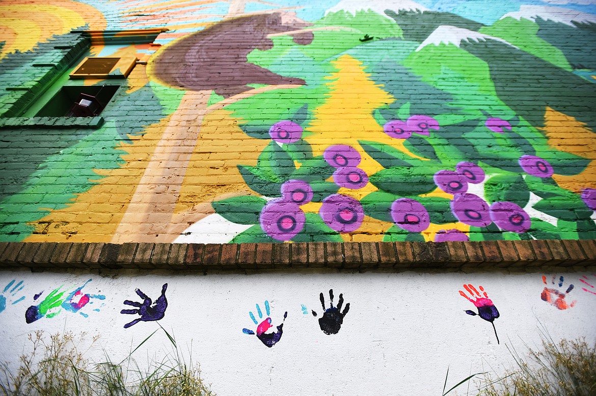Painted hand prints decorate a wall below a mural created by Thomas Valencia along West Center Street and Fifth Avenue West in Kalispell on Tuesday, Aug. 4. Valencia is asking for the community's help in filling the horizontal panel with hand prints, as long as you don't mind getting spray paint on your hand. (Casey Kreider/Daily Inter Lake)