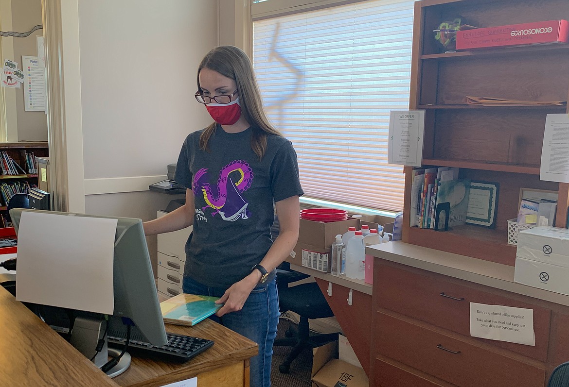 East Adams Library District Director Kylie Fullmer scans books behind the desk at Ritzville Public Library on Wednesday afternoon. Fullmer said it’s been stressful, at times, “completely shifting” how the library operates.