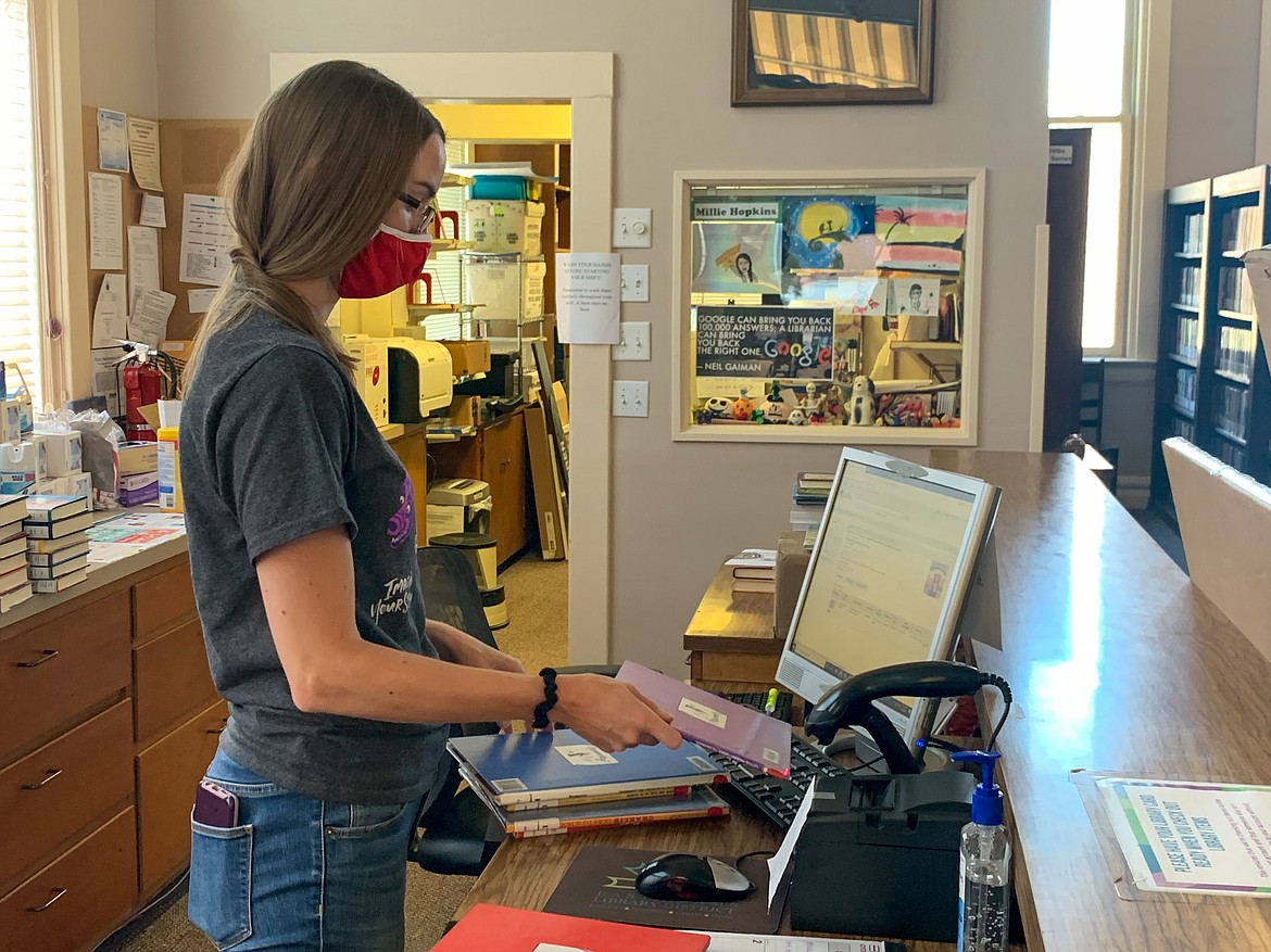 East Adams Library District Director Kylie Fullmer scans books behind the desk at Ritzville Public Library on Wednesday afternoon. Fullmer and her staff have worked to shift their programs and services to continue to serve the community.