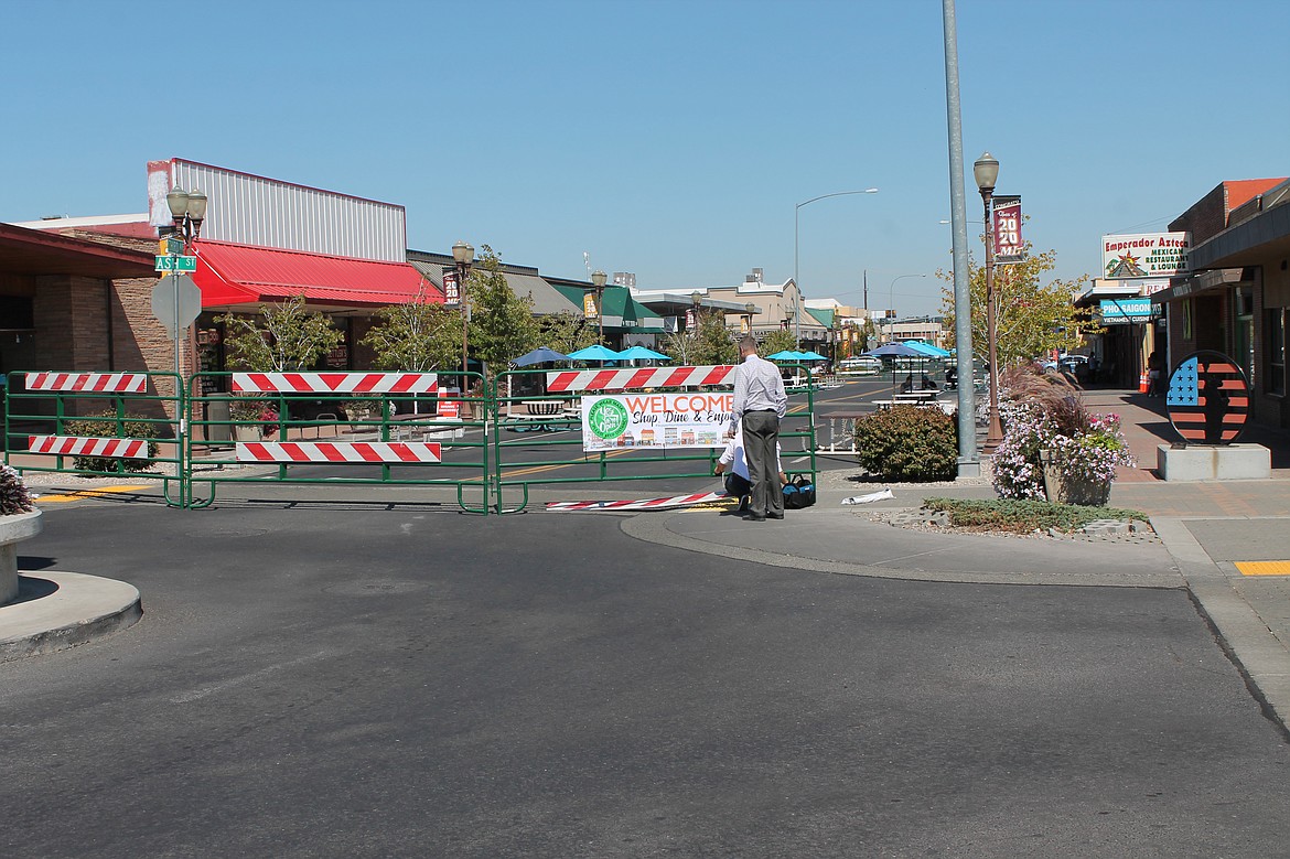 James Shank and Brandon Nicholas (partially obscured) hang out signs showing that a block of Third Avenue in Moses Lake is closed to vehicles.