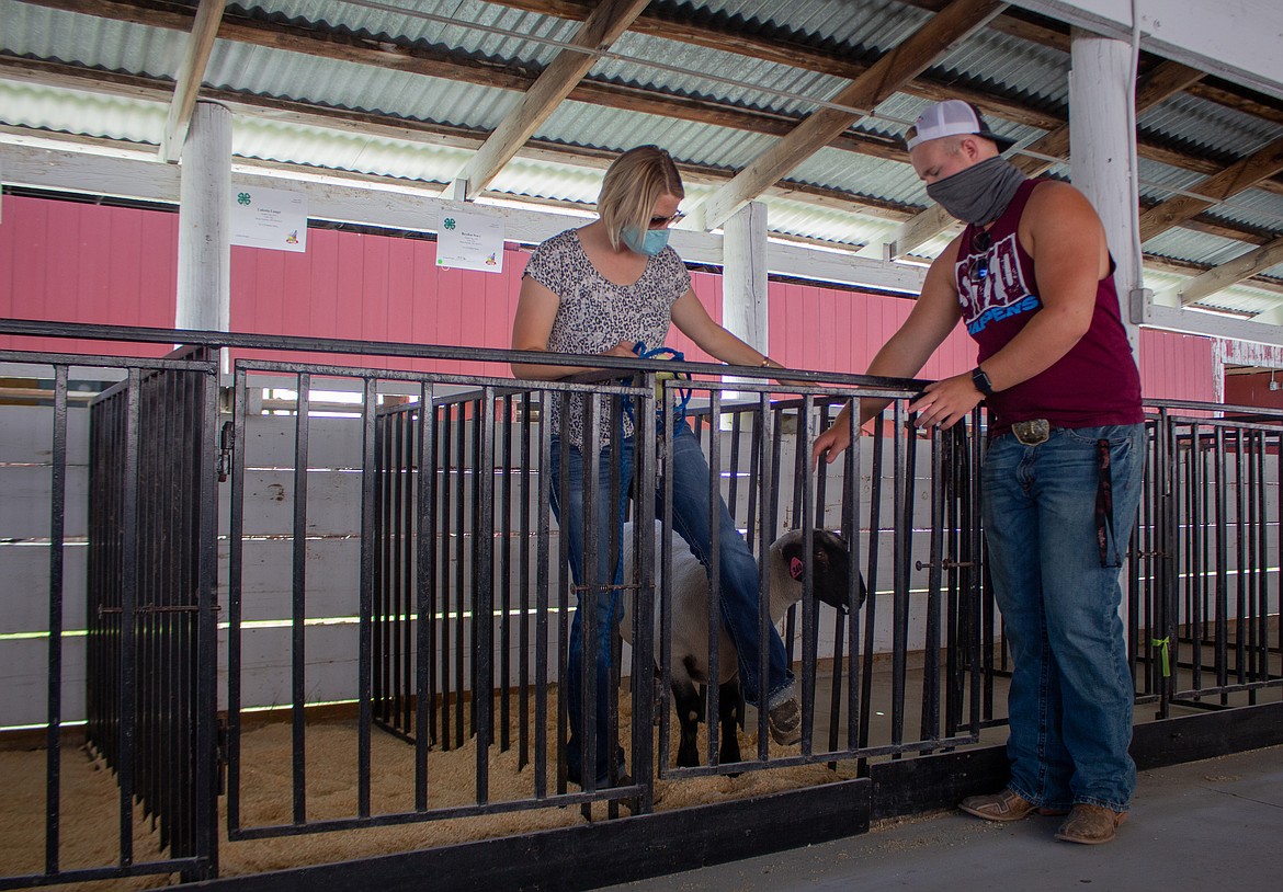 Samantha Rodeback and Rhody Raymond try to entice the sheep to stay inside the pen as Rodeback tries to make her way back out on Wednesday afternoon at the Grant County Fairgrounds.