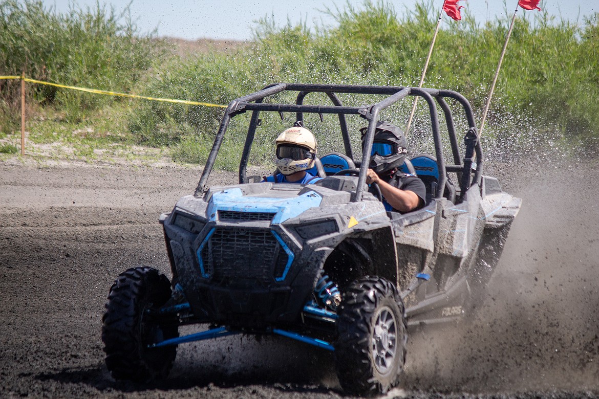Casey McCarthy/Columbia Basin Herald 
 Ben Vaughn is behind the wheel with Roberto Chavez in tow in the passenger seat as the two send mud and sand into the air making their way around the track at the annual Off Road Race Around the Bowls event on Saturday.