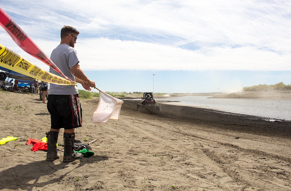 Casey McCarthy/Columbia Basin Herald
Brandon Douglass waves the white flag from the edge of the race track at the Sand Scorpions ORV Group’s annual Off Road Race Around the Bowls event.