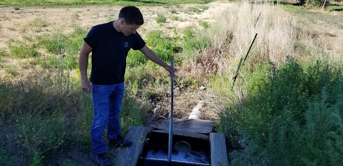 Nate Volkov measures how much water is going over the top of the weir into a farmers field.