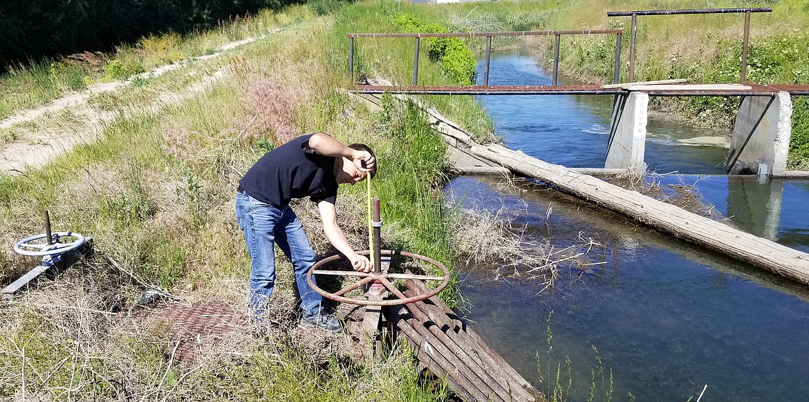 Nate Volkov measures the stem sticking up out of the weir to ensure that the right amount of water is being sent down the ditch. The Trinidad Wasteway is in the background.