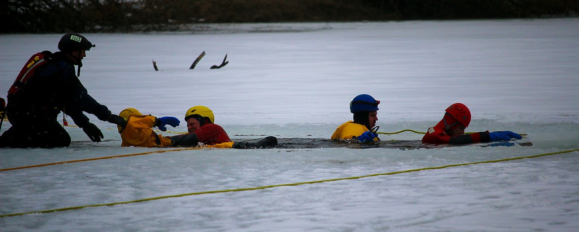 The firefighters worked together to pull one of their team members out of the water.