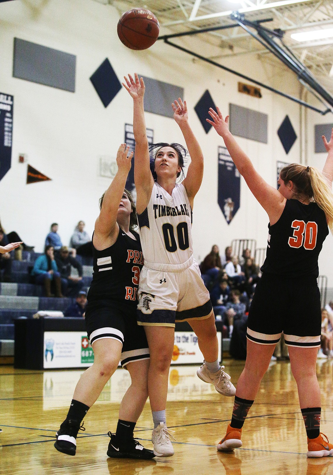 Timberlake’s Karina Sande scores on a layup while defended by Priest River’s Abby Shockey, left, and Adrie Minish during Monday’s game at Timberlake High School.