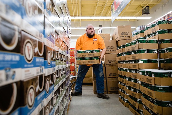 Isaac White, customer satisfaction expert with Bi-Mart, organizes a display of coffee.