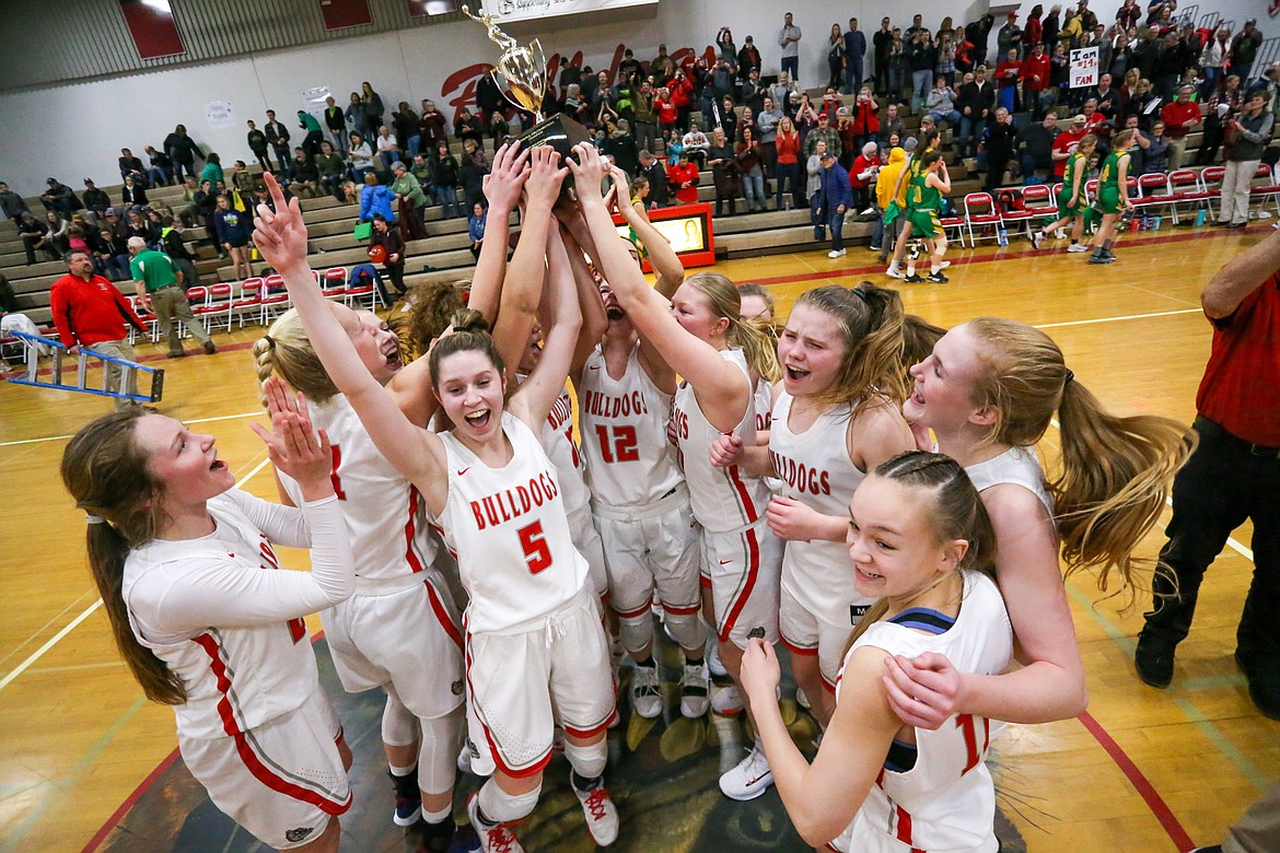 (Photo courtesy of JASON DUCHOW PHOTOGRAPHY) The Sandpoint girls basketball team celebrates with the district championship trophy after taking down Lakeland 48-44 Friday night. The Bulldogs are now heading to state.