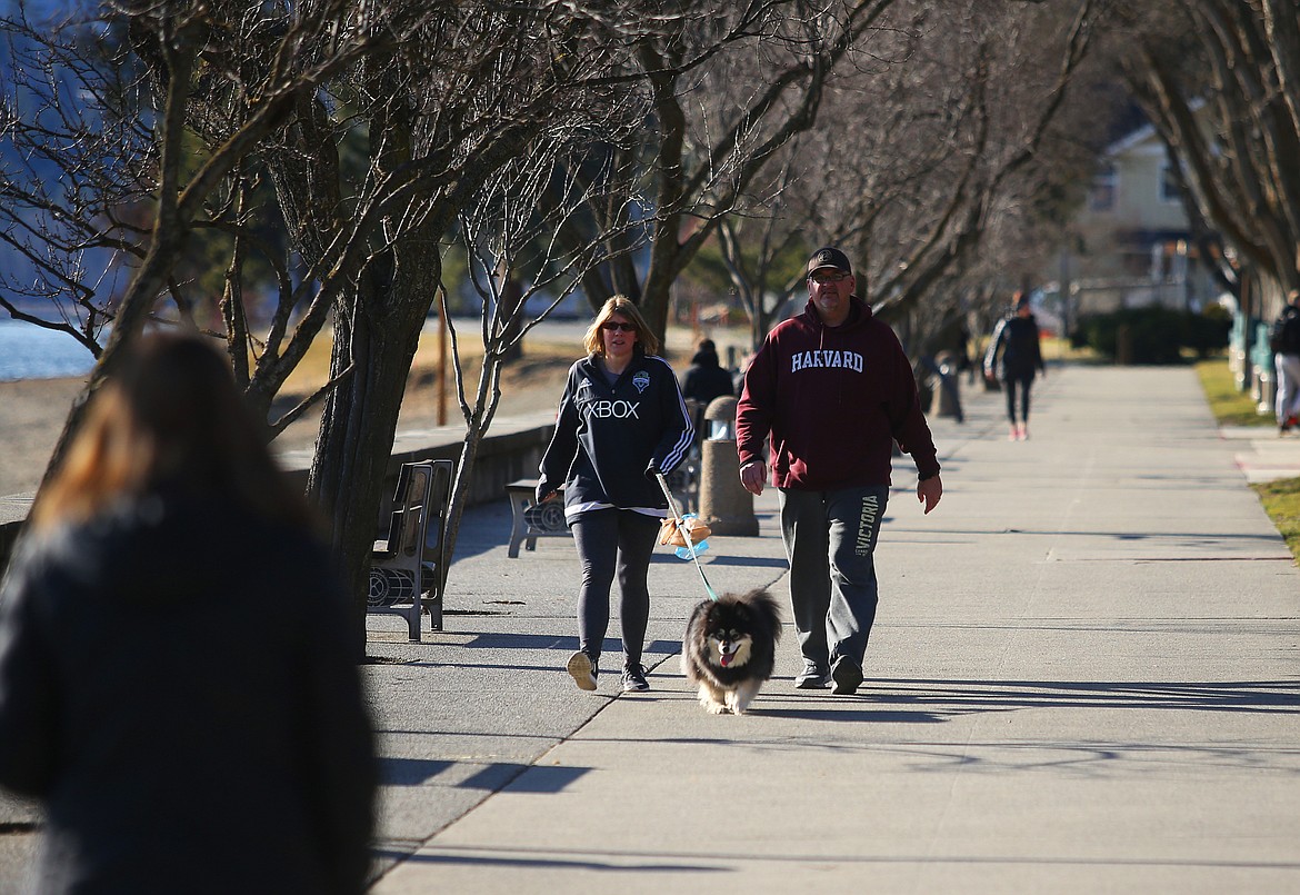 Coeur d’Alene residents Tony and Stacy Norris walk their dog, Moka, along the North Idaho Centennial Trail Wednesday near City Beach.
