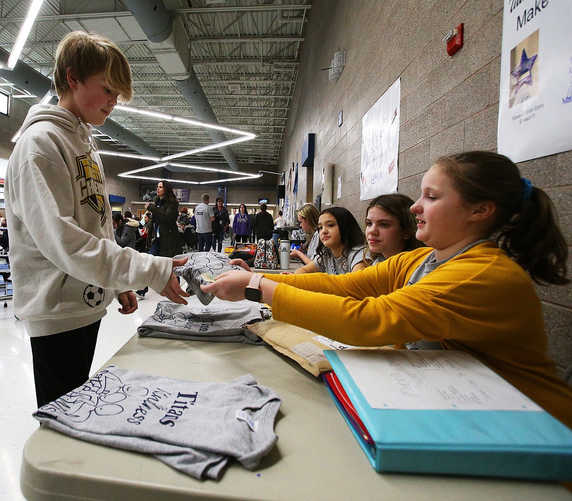 Eighth grade student Carson Sullivan donates $12 to Make-A-Wish and gets a T-shirt from seventh grade ASB vice president Maddie Short during River City Middle School’s Kindness Week.