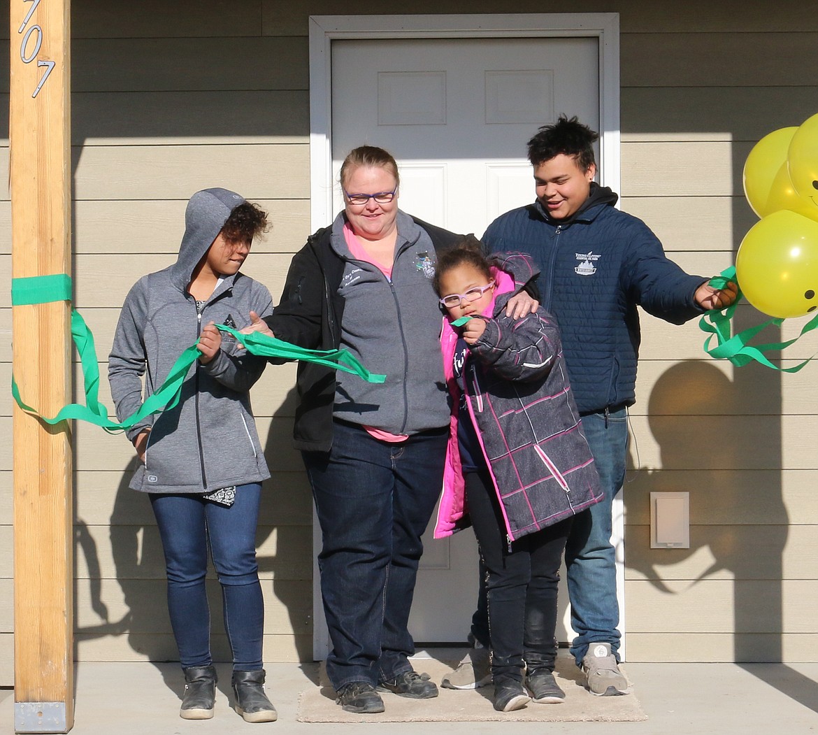 The Wolf family tears down the ribbon, opening the door to their new house from Boundary County Fuller Center for Housing.