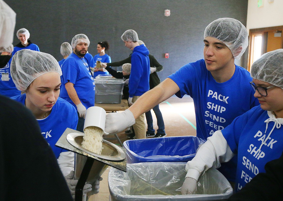 Sophomore Caden Scott pours a serving of rice into a funnel during a Feed the Need packing party at North Idaho Christian School on Thursday. Feed the Need is a global organization through which schools can participate in service projects to help those in need around the world.