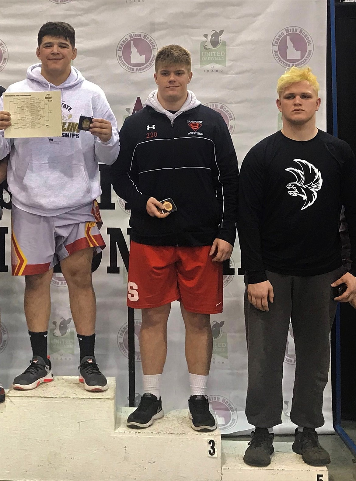 Junior Tag Benefield (middle) stands atop the podium after placing third at 220 pounds in the 4A state championships Saturday.