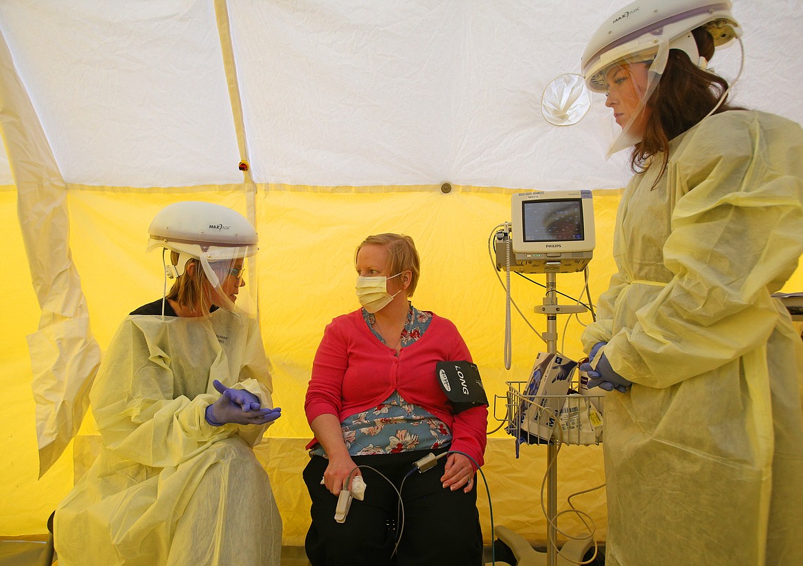 Kootenai Health physical assistant Natalie Koncz, left, and registered nurse Emily Cheeseman attend to practice patient Karly Vesely during a test run for hospital staff Wednesday. The tent allows emergency staff to test people for COVID-19. (LOREN BENOIT/Press)