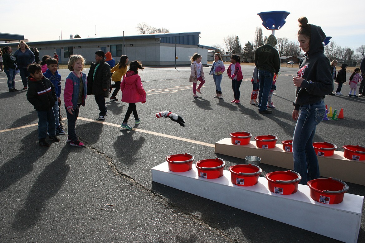 Emeri Mackey (right) of the Moses Lake High School FFA chapter supervises the Cat in the Hat ring toss on Dr. Seuss Day at Knolls Vista Elementary Wednesday.