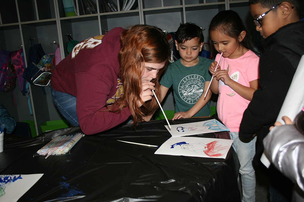 Moses Lake High School FFA member Shyanne Knowles demonstrates paint blowing techniques for Knolls Vista students on Dr. Seuss Day Wednesday.