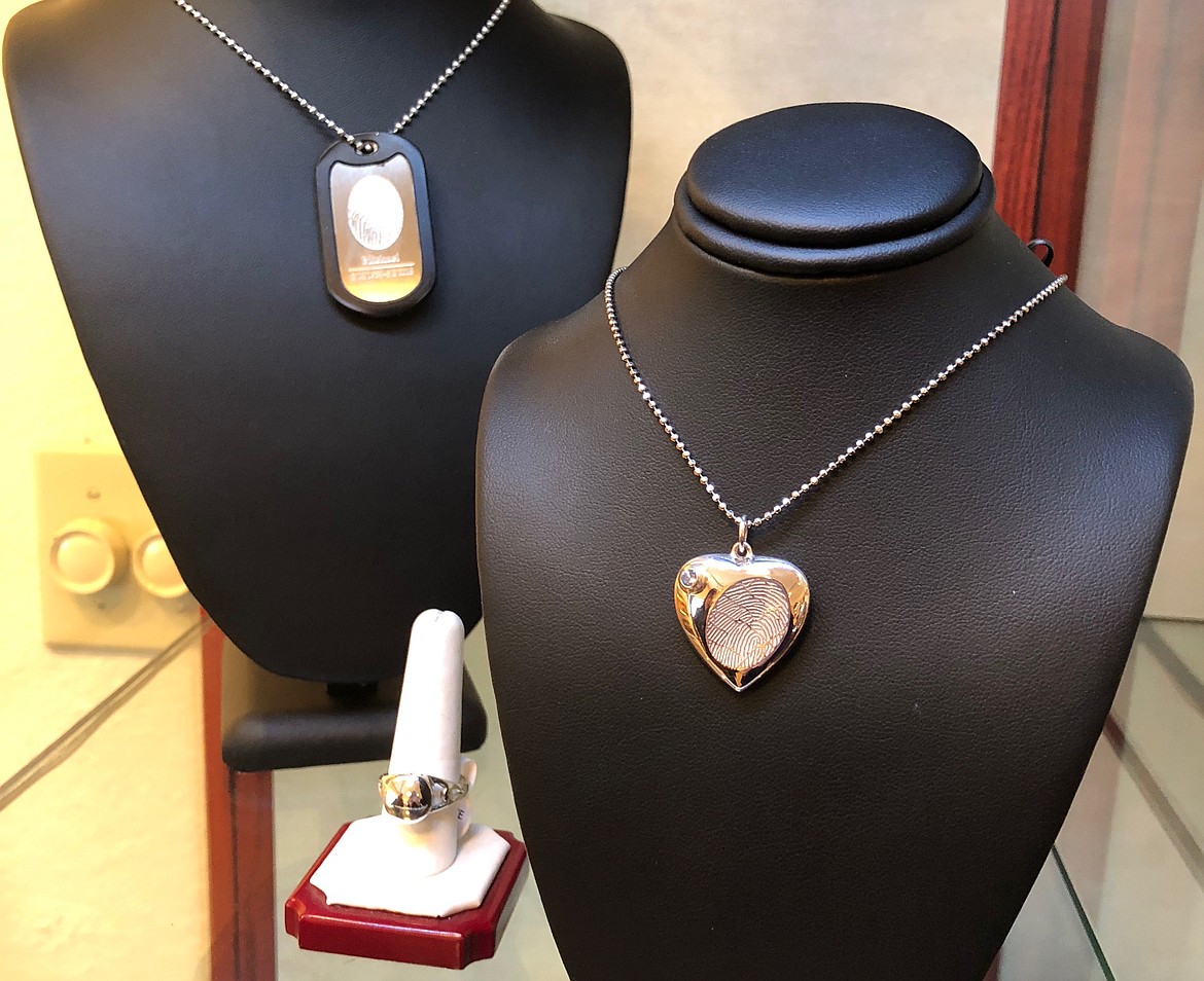 Keepsake necklaces featuring thumbprints and a gemstone compartment for a loved one’s remains on display in the selection room.