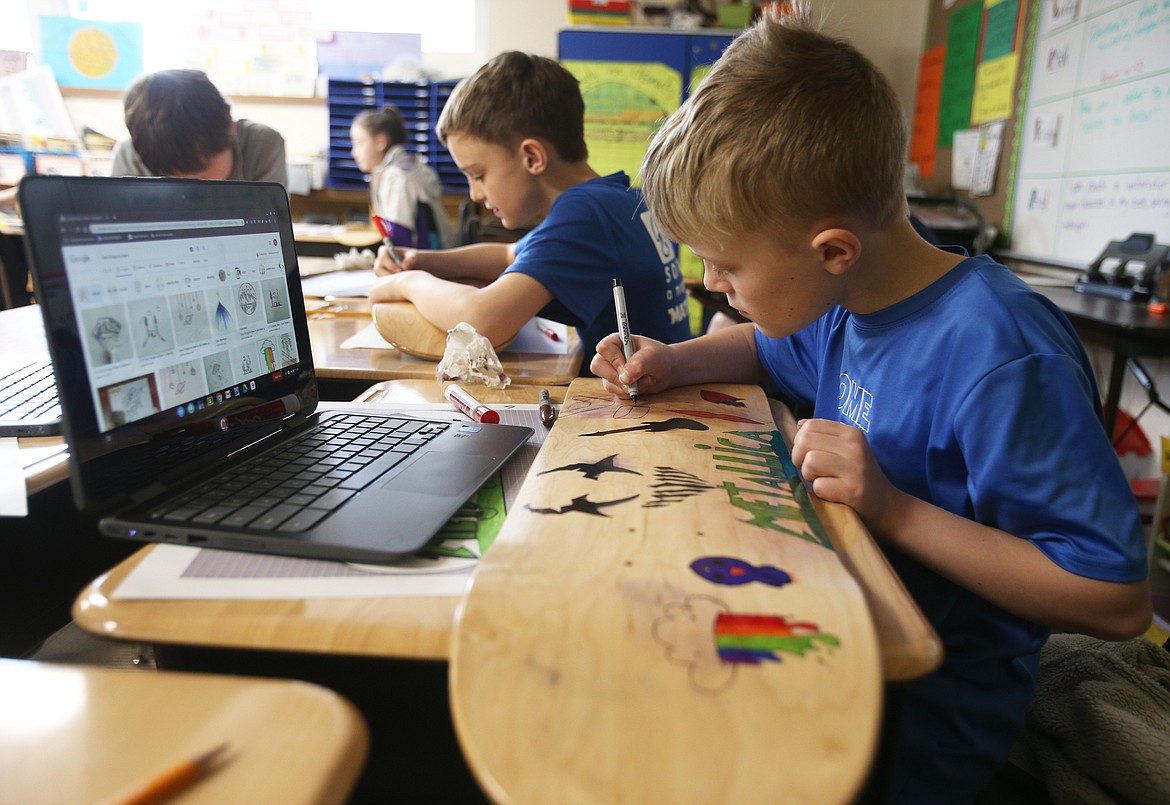 Fifth-grade student Bridger DeMoe uses a marker to draw band symbols on his Metalica skateboard during class Wednesday at Sorensen Magnet School of the Arts and Humanities. (LOREN BENOIT/Press)