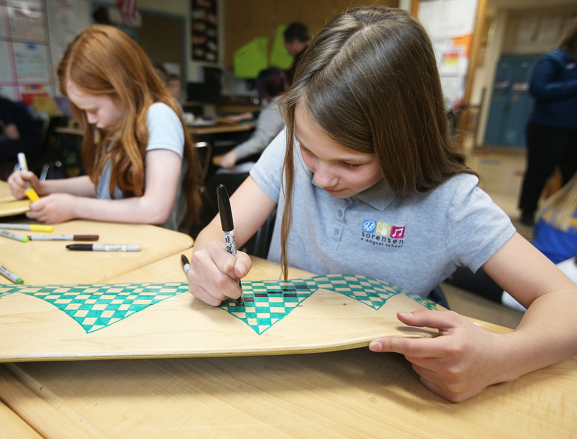 Fifth-grade students Ellie Holm, left, and Zaria Metts paint designs on their skateboards as part of the school’s Artist-in-Residence program with skateboard artist Mark Rivard on Wednesday. (LOREN BENOIT/Press)