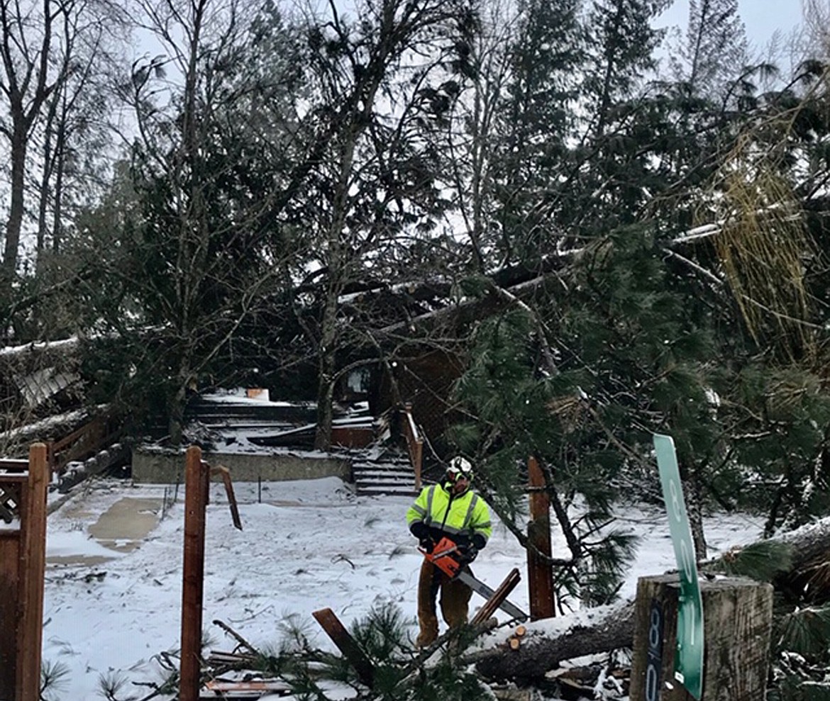 Avista employees work on the ground and in the air on Upland Drive on Saturday to restore power for residents. This house was severely damaged by the storm.