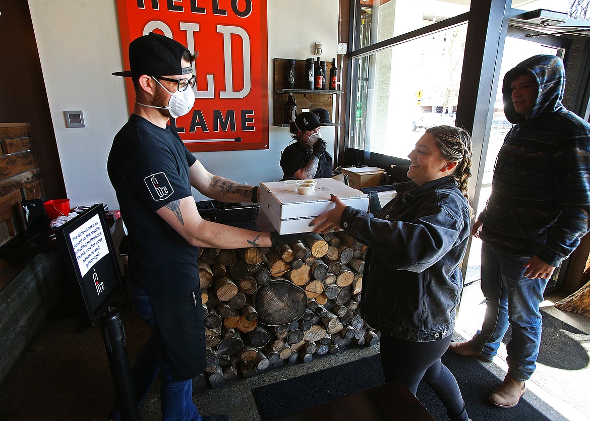 Abigail Paderson picks up her family's pizza order from Fire Artisan Pizza employee Jeromy Hebert on Wednesday. Curbside pickup and delivery options are helping customers — and local restaurants — through COVID-19. (LOREN BENOIT/Press)