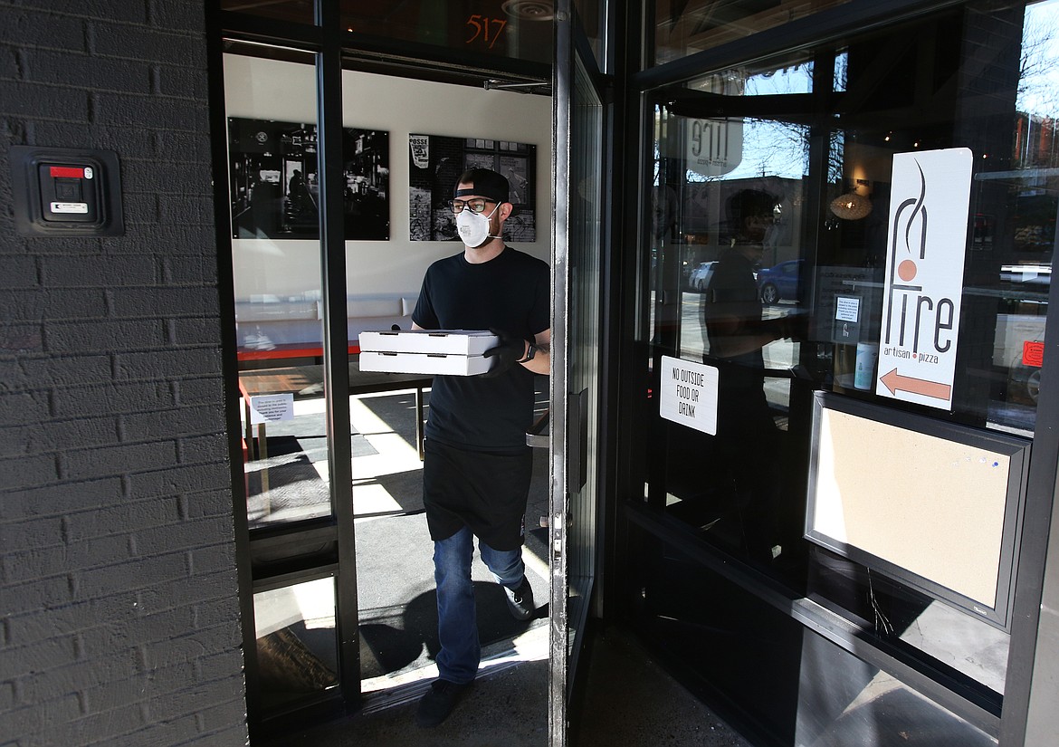 Fire Artisan Pizza employee Jeromy Hebert makes his way out to a curbside order Wednesday. Curbside pickup and delivery options are helping customers — and local restaurants — through COVID-19. (LOREN BENOIT/Press)