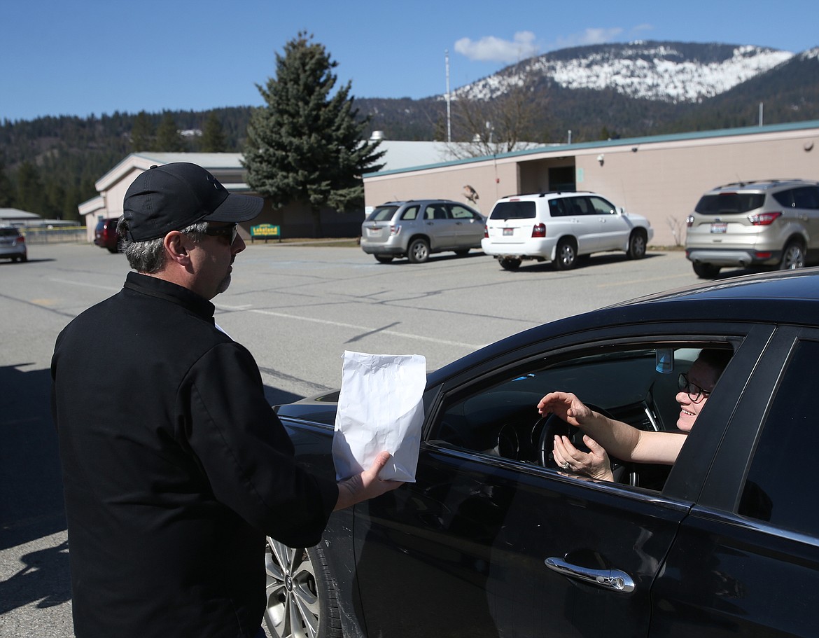 Lakeland Nutrition Services director Kevin Doyle delivers one of three lunches for parent Michelle Ohlenkamp during Lakeland Junior High’s Grab-and-Go lunch on Friday. Lakeland is offering Grab-and-Go meals Monday through Friday from now until at least April 3 at Athol Elementary from 9:45 to 10:15 a.m., at Timberlake High from 10:45 a.m. to 11:15 a.m. and at Lakeland Junior High from noon to 12:30 p.m. Each student will receive one breakfast and one lunch.