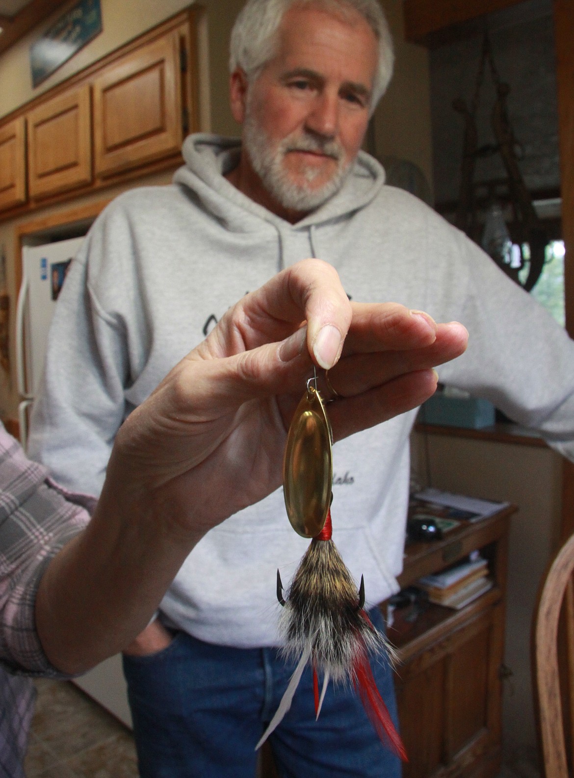 Fishing guide Don Houk, checks out a Knotty Scotty pike spinner that his wife, Susan, holds. The lures, named after their son, Scott, who developed them, have also become regional favorites. They are made in the Houks’ Kidd Island Bay tying room, and are often pieced together in the couple’s living room.