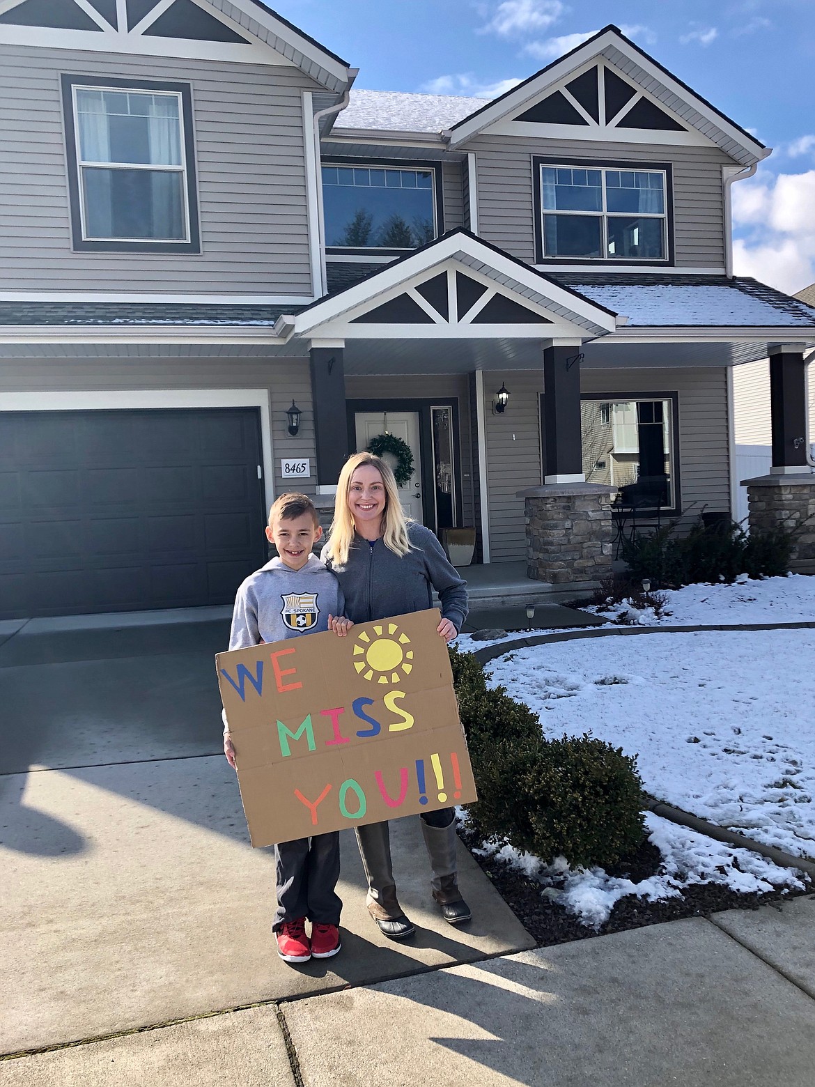 Atlas Elementary student Henry Weimer-Earnest and his mom Courtney Weimer let teachers know they miss them with a colorful sign during the Atlas teacher car parade Wednesday. (Courtesy photo)
