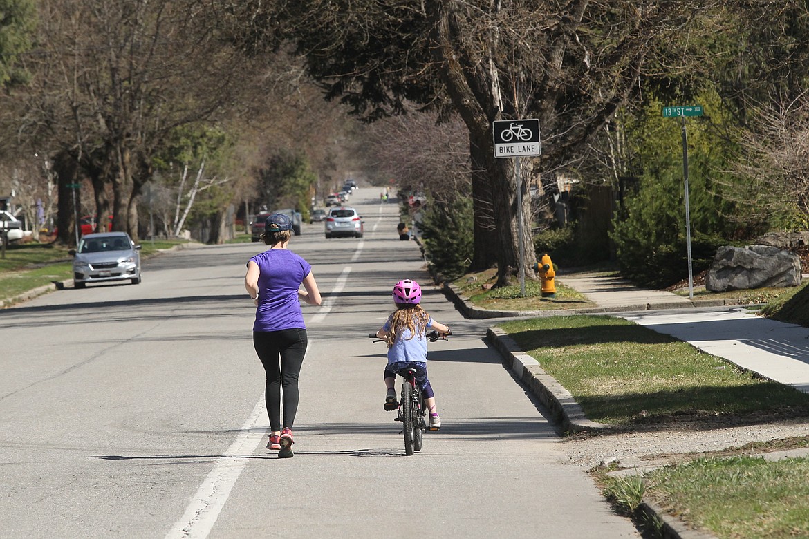 Katie Pemberton and daughter Ellie Pemberton get some exercise in on a sunny Wednesday as they run and bike on Mullan Avenue in Coeur d’Alene.