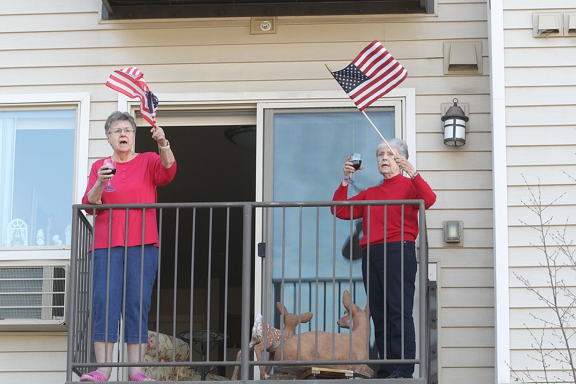 Donna Orr, left, and Darlene Blomgren, from their balcony, join in some patriotic songs at Affinity at Coeur d’Alene on Friday afternoon.