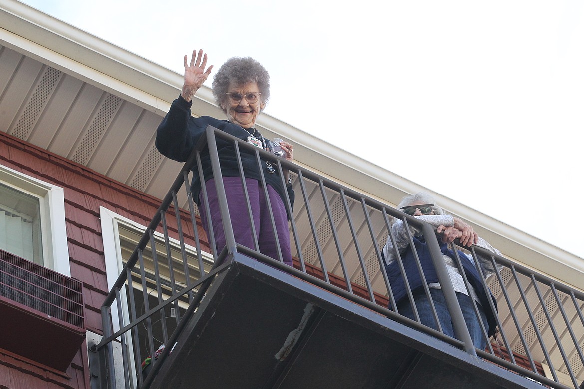 BILL BULEY/Press 
 Darlene Nicholson, left, and Laurie Macklin wave from their balcony at Affinity at Coeur d'Alene, a 55-plus living community, after singing God Bless America on Friday