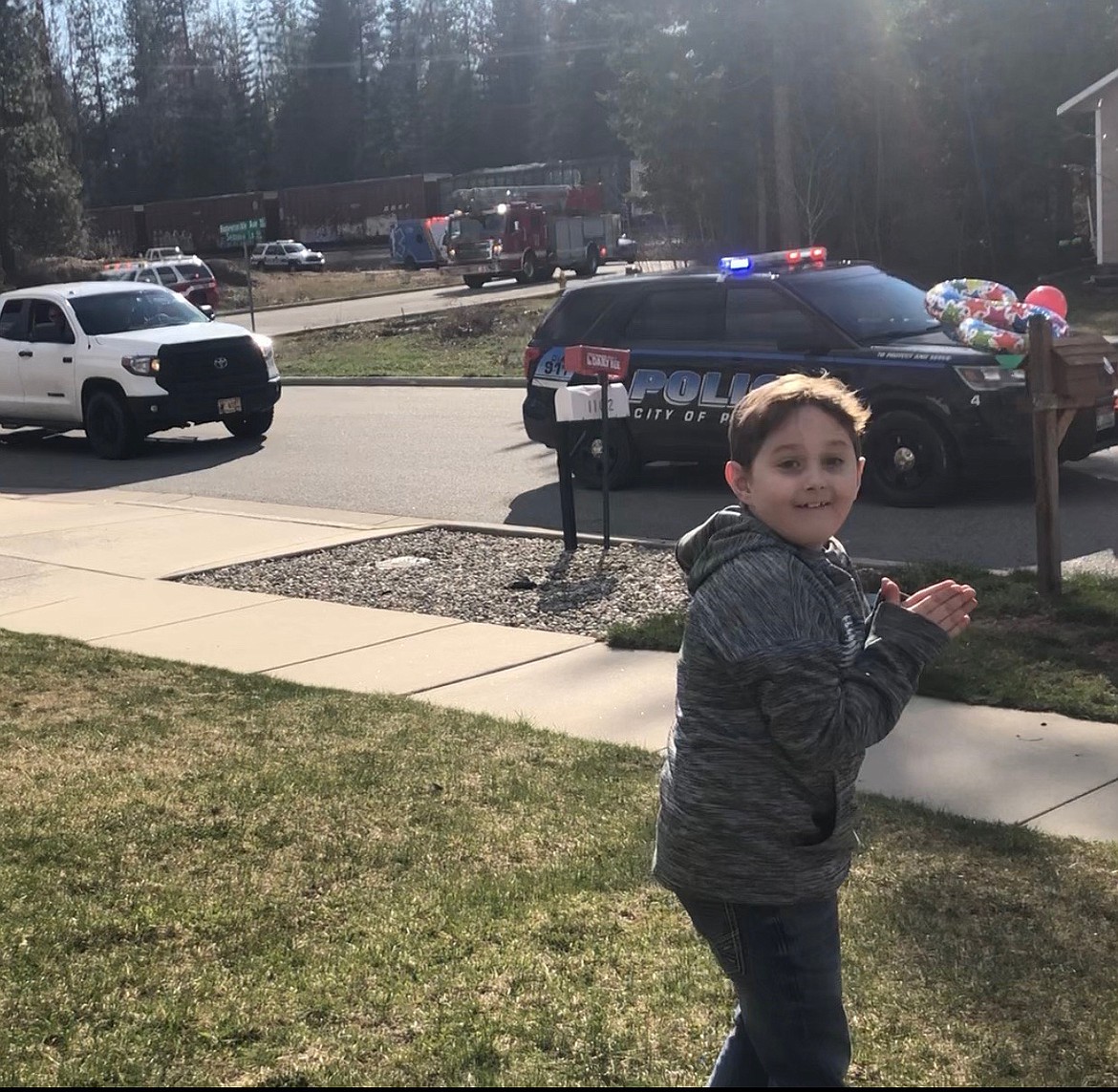 (Courtesy photo) 
 Jackson Reynold looks on in surprise as several dozen police cars, fire trucks, Sandpoint Subaru Club members and others make their way past his home Saturday in a special parade to wish the now-8-year-old a happy birthday.
