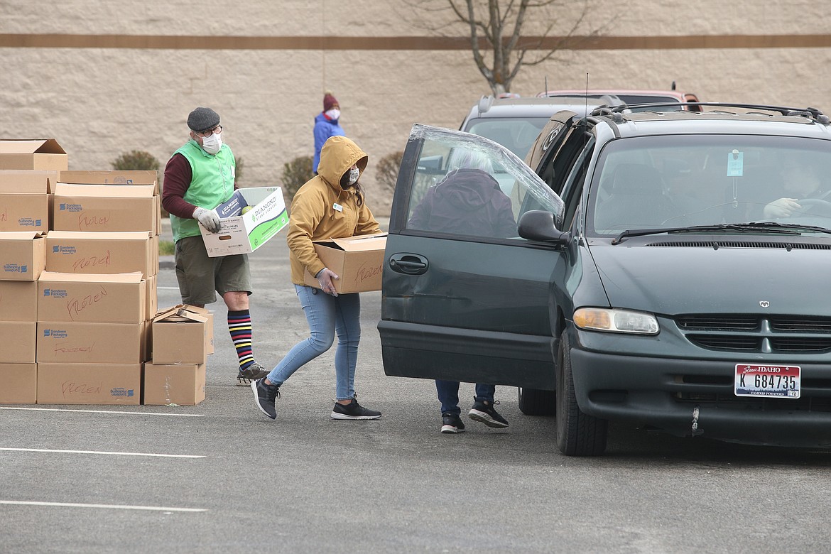 Second Harvest volunteers Kevin Miller and April Lopez carry food to a van during Wednesday’s free food distribution at the Silver Lake Mall.