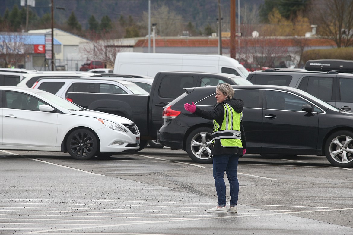 BILL BULEY/Press 
 Melissa Schock directs traffic iinto parking lanes as drivers wait their turn to receive food at Second Harvest's distribution on Wednesday.