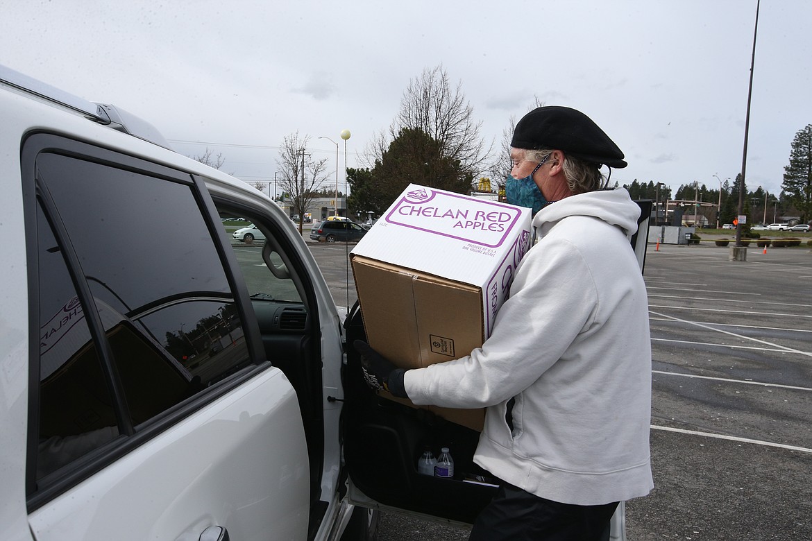 BILL BULEY/Press 
 Kevin Jester places a box of food into a car at Wednesday's food giveaway.