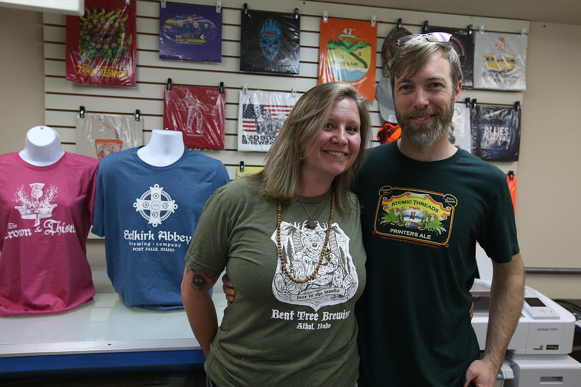 Andrew Willis and wife Jami Daugherty pose at their local business, Atomic Threads. To help other local businesses during the COVID-19 pandemic, Atomic Threads has begun a fundraiser which produces a T-shirt with the logo of customers’ favorite local business while also making a $10 donation to that business.