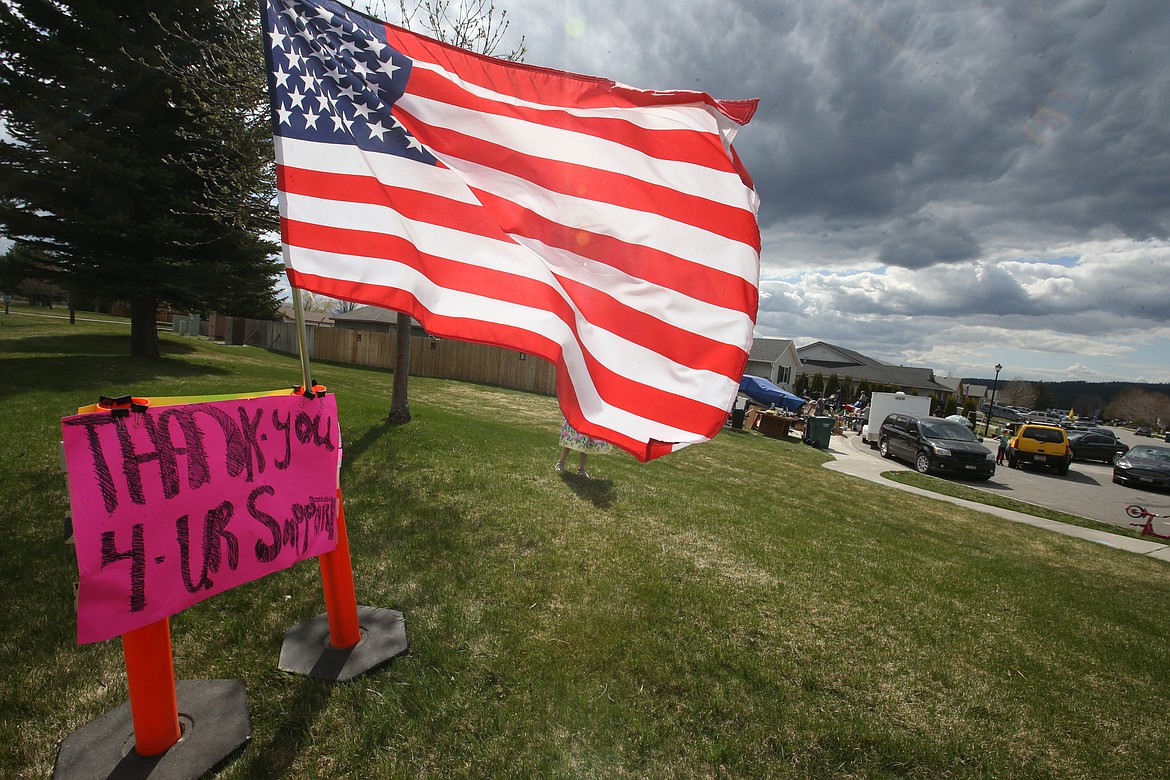 A U.S. flag flutters in the wind near the Rathdrum home of Peter and Christa Thompson on Monday. The Thompsons continued with their yard sale, despite being cited by police on Friday.