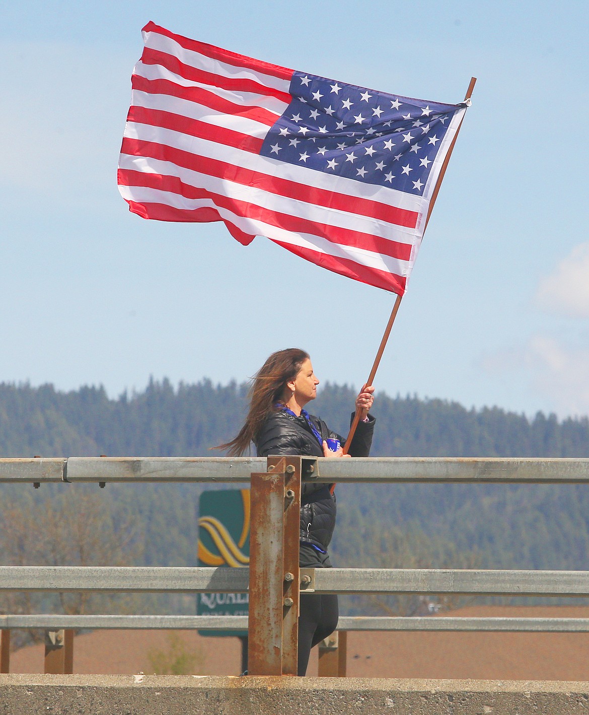 BILL BULEY/Press 
 Della Bennett carries a flag as she walks along U.S. 95 during Sunday's free rally in Coeur d'Alene.